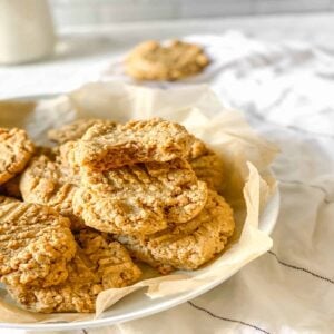 vegan peanut butter cookies in a white bowl on a white and black striped dish towel