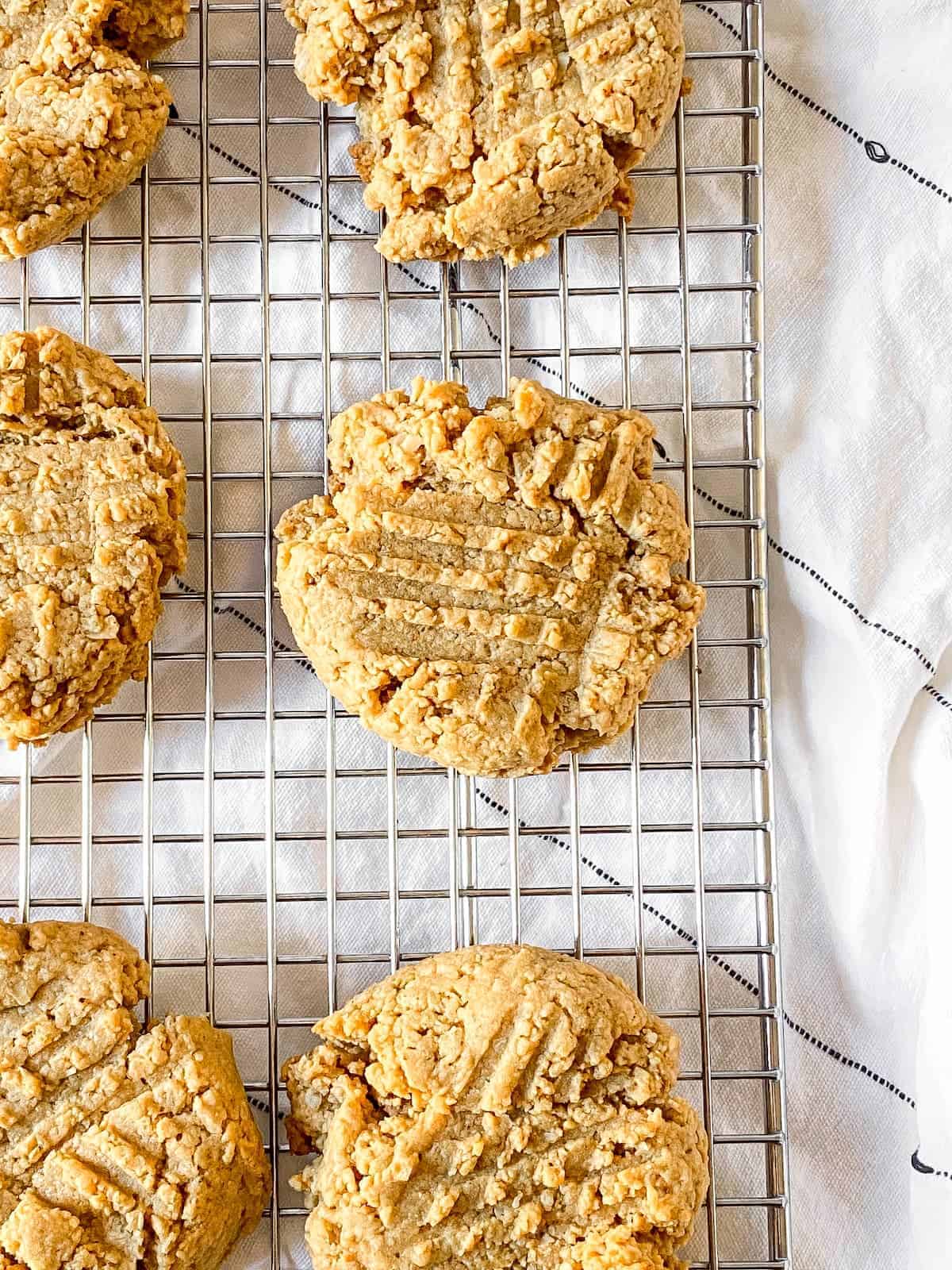 Peanut butter cookies on a wire cooling rack on top of a dish towel.