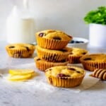 three lemon blueberry muffins stacked with other muffins surrounding