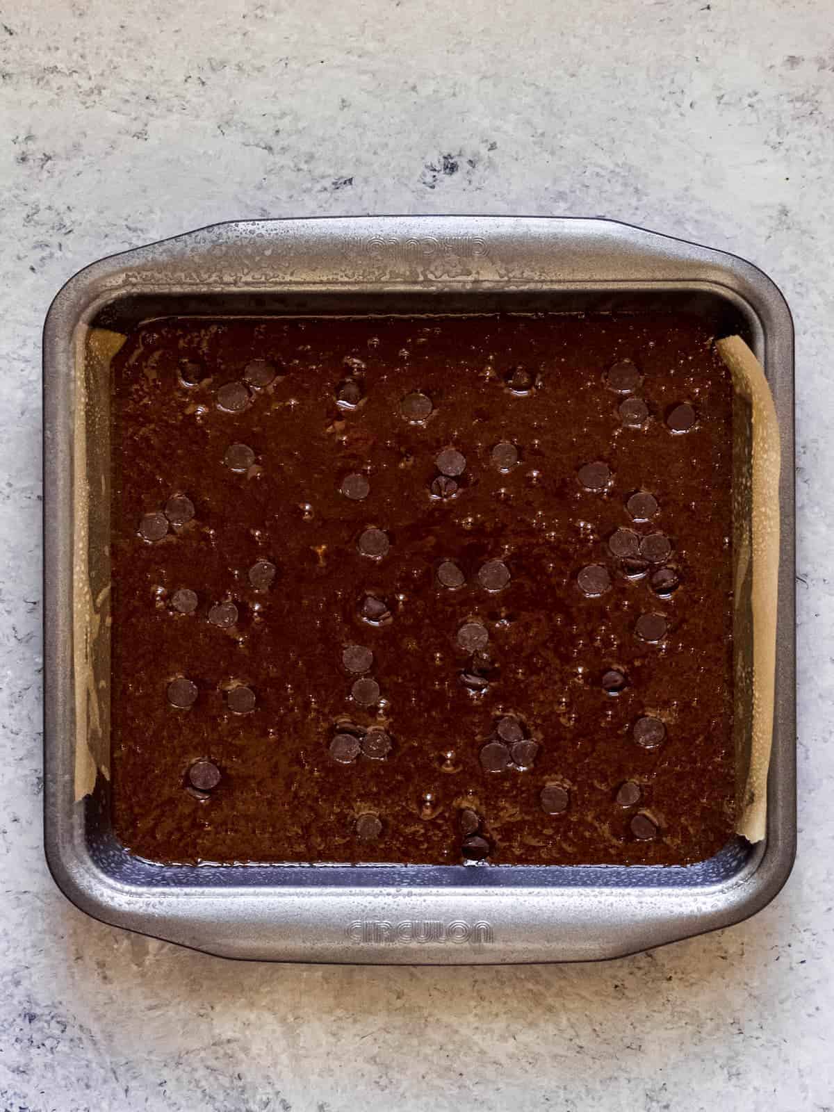 Brownie batter in a silver square baking pan.