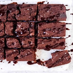 brownies cut into squares and drizzled with melted chocolate and sea salt on wax paper