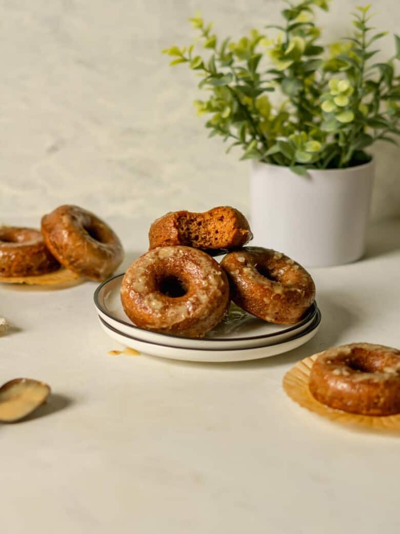 Three donuts on a white plate topped with a maple syrup glaze.
