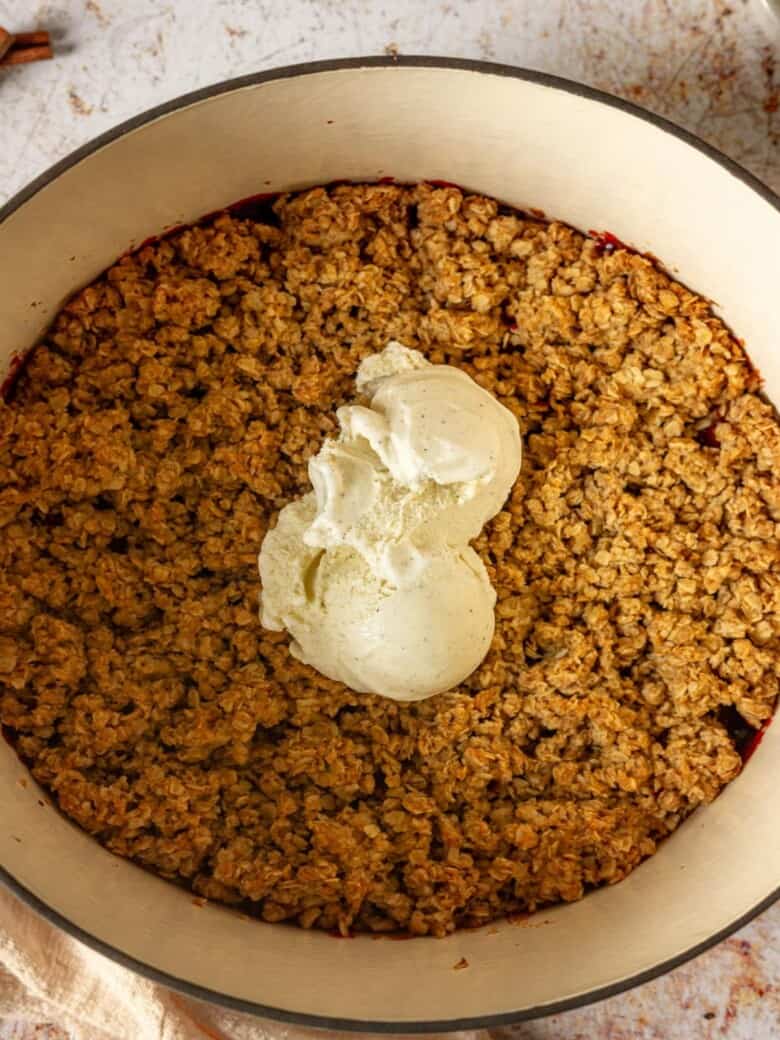 Dutch oven apple and cranberry crisp topped with vanilla ice cream.
