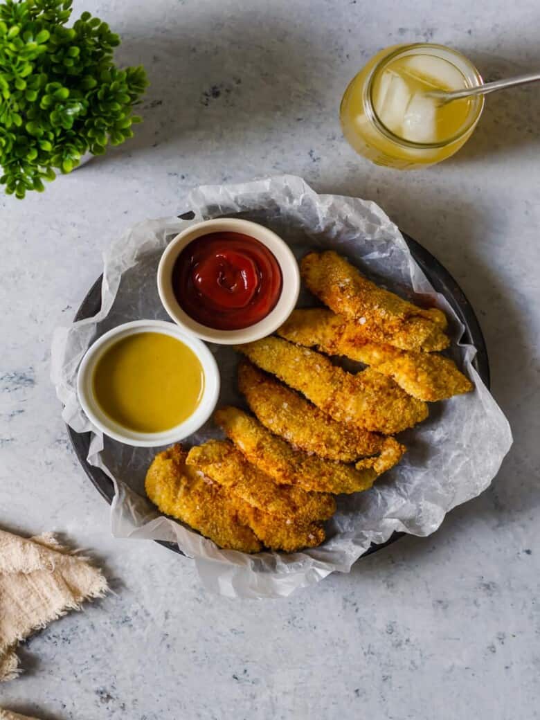 Air fryer chicken tender tray with sauces and a cocktail.