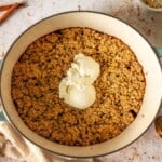 A Dutch oven filled with crisp topped with vanilla ice cream.