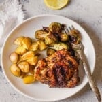 A plate filled with a lemon pepper seasoned chicken thigh and veggies.