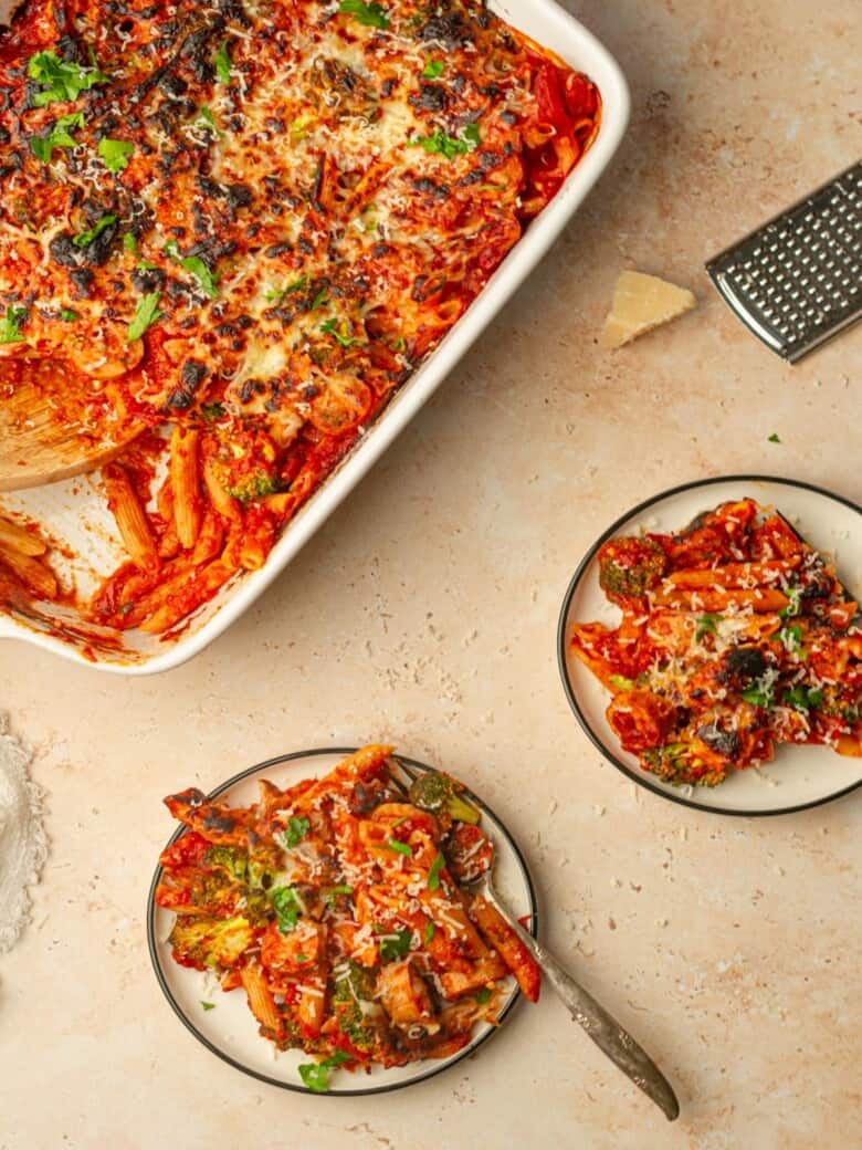 Two plates of baked pasta with a casserole dish full of no boil pasta bake.