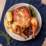 Blue napkin topped with a plate full of a rotisserie chicken.