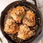 Chicken thighs in a cast iron pan topped with thyme.