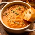 A bowl of pumpkin soup garnished with thyme.