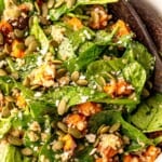 A spinach and sweet potato salad with salad spoons.