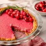 A piece taken out of cranberry tart garnished with cranberries.