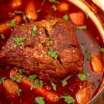 Cooked chuck roast in broth in a large pot.