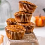 Pumpkin muffins stacked on top of a loaf pan.