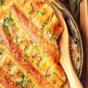 A pot pie with a wooden spoon digging in.