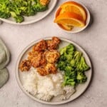 A plate of breaded orange chicken with white rice and steamed broccoli.