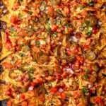 Shredded chicken nachos topped with tomatoes.