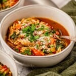 A bowl of minestrone soup with parmesan and parsley.