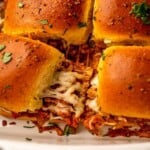 Two sliders with cheese in a baking dish.