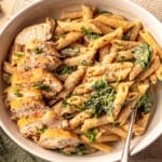 A bowl of pasta topped with sliced chicken.