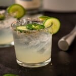 A margarita with a salt rim garnished with jalapeño slice and cucumber slices.