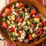 Chopped cucumbers, tomatoes and feta cheese salad in a wooden bowl.