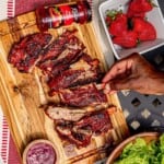 A hand grabbing a rib from a cutting board.