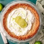 A key lime pie in a clear pie dish.