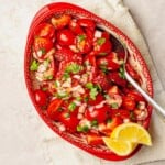 Strawberry and tomato salad in a red bowl.