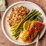 Couscous, asparagus and a piece of breaded fish on a plate.