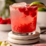 A raspberry cocktail on coasters.