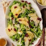 Pear and arugula salad on a plate next to wooden salad spoons.