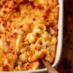 A spoon scooping into a pan of mac and cheese.