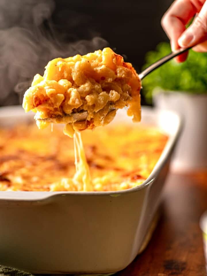 A spoon lifting up steaming macaroni and cheese.