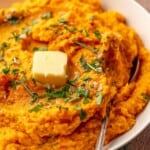 Mashed sweet potatoes topped with parsley and a piece of butter.