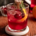 A cranberry drink garnished with rosemary.