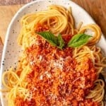 Chicken bolognese on top of spaghetti.