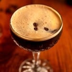 An espresso martini topped with coffee beans.