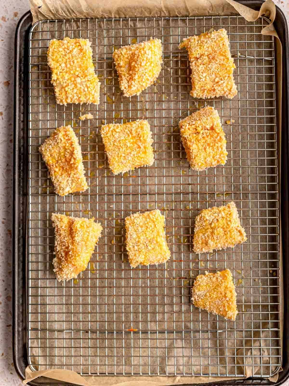 Breaded fish pieces on a baking sheet.