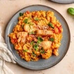 Seafood risotto topped with chopped basil on a plate.