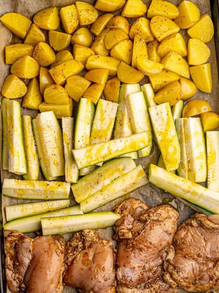 Yellow potatoes, zucchini and chicken thighs on a sheet pan.