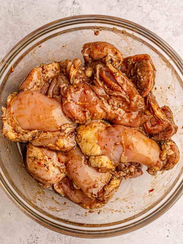 Chicken marinading in a glass bowl.