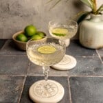 Tequila sour cocktails in coup glasses with lime slices.