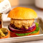 Cheese on a chicken burger with lettuce, tomato and onion.
