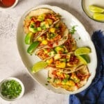 White platter filled with shredded chicken tacos.