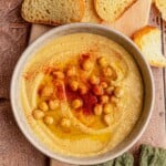A bowl of hummus topped with chickpeas and paprika.
