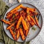 A plate of carrots topped with rosemary.