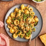 A blue plate of pasta with peas.
