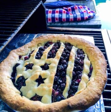 Blueberry pie with American flag lattice on a grill.