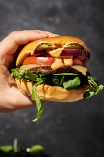 Portobello mushroom burger on a bun, pickles, red onion, tomato, lettuce and cheese.